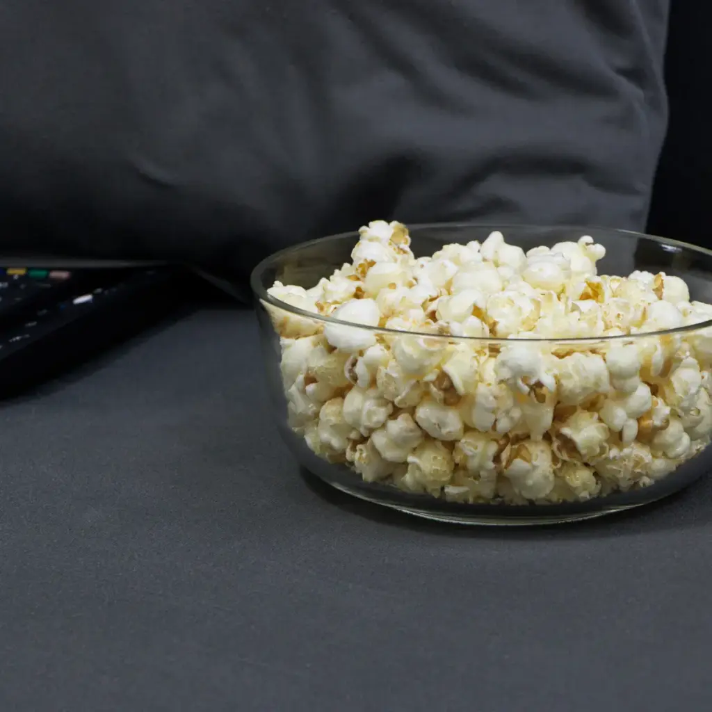 Schale mit Popcorn und Fernbedienungen auf einem Sofa