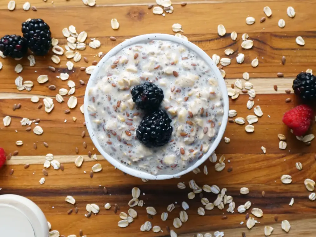 Schale Haferbrei mit Beeren und Haferflocken auf einem Holztisch