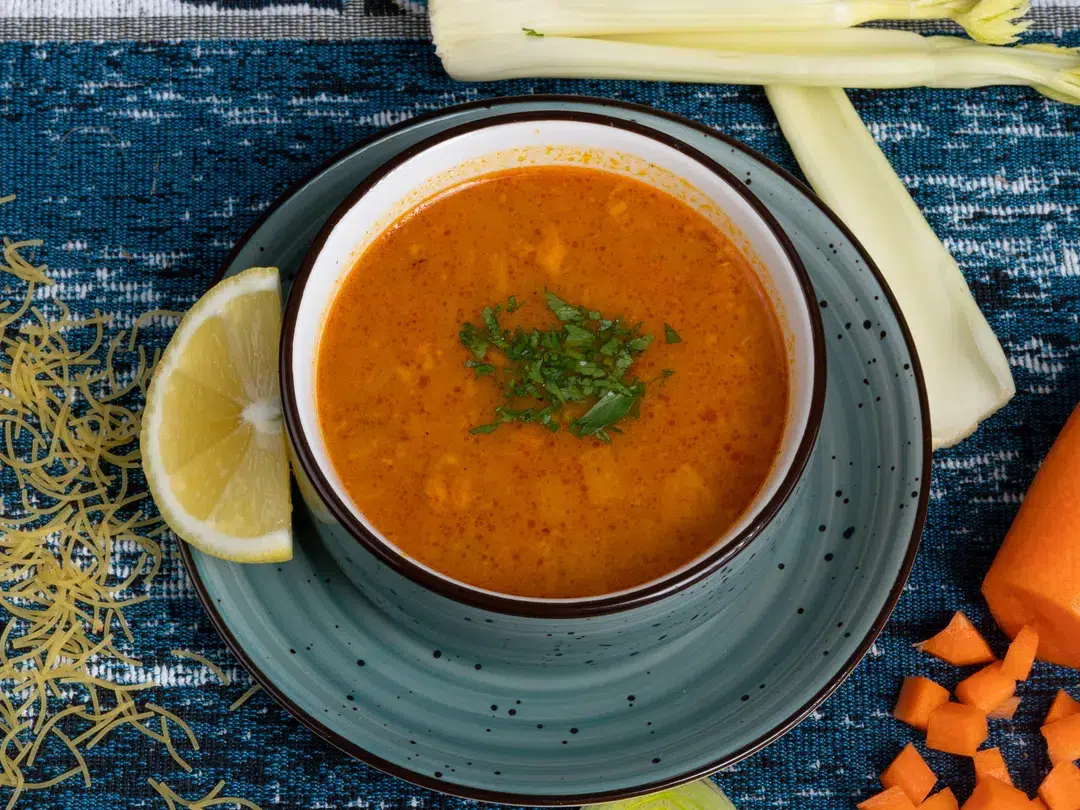 Schale mit roter Linsensuppe, Zitrone und Petersilie, von oben fotografiert